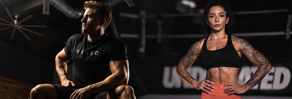 Male and female athletes posing in a dim gym, man seated and woman standing with hands on hips, showcasing muscular physiques