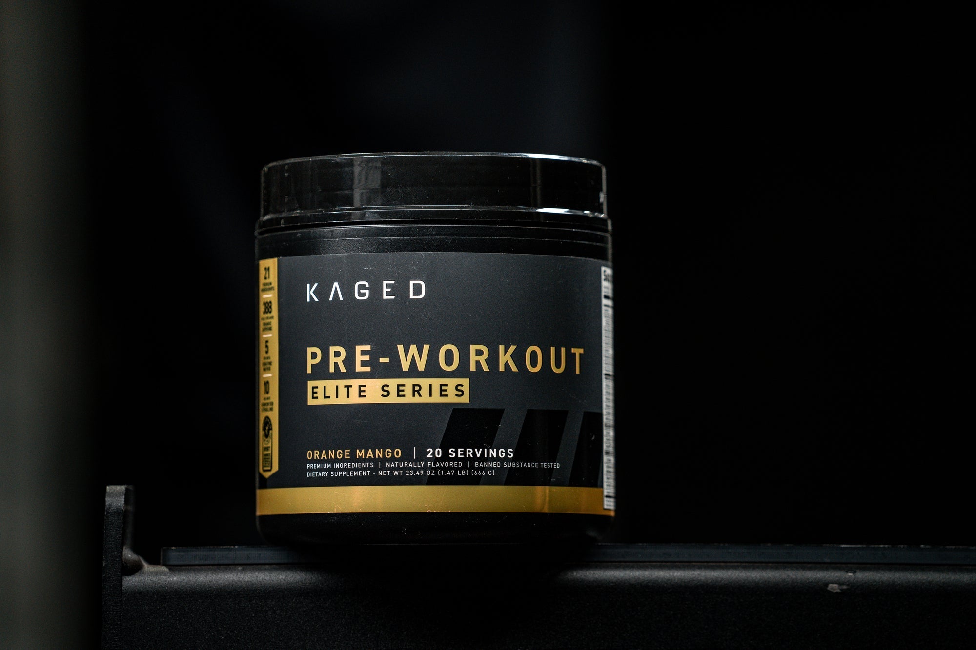 Front view of KAGED Pre-Workout tub with black-and-gold PRE-WORKOUT label and Orange Mango flavor on dark background