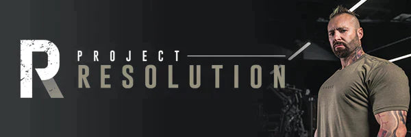 Male trainer standing in a dark gym beside a large banner reading Project Resolution