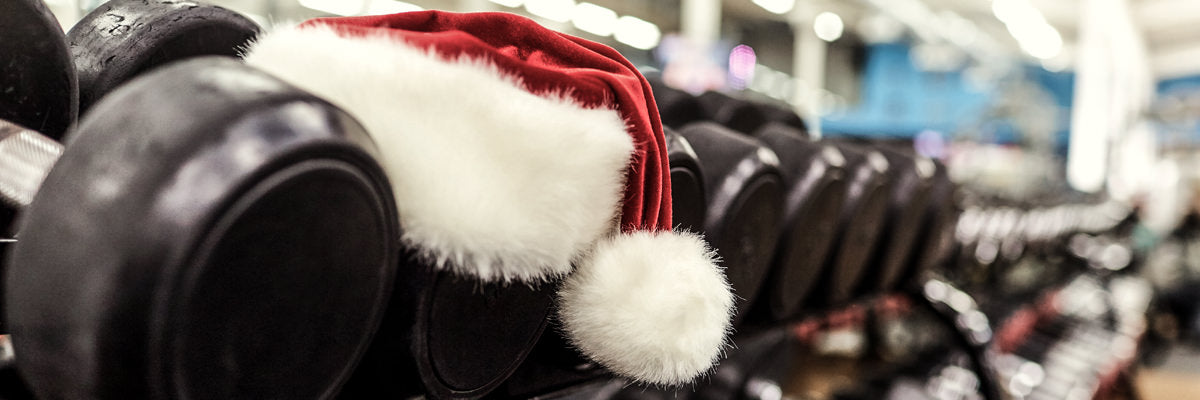 Santa hat draped over a row of dumbbells in a gym, holiday-themed image for a gift guide