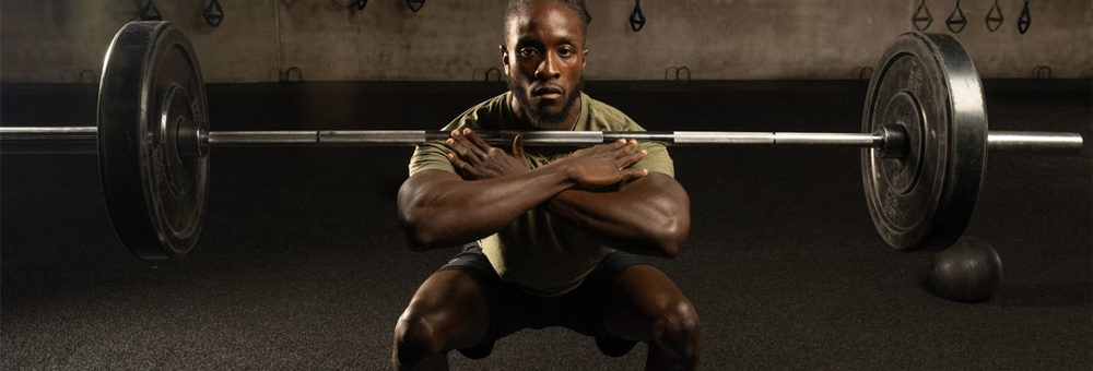 Athlete performing a front squat with a loaded barbell in a dim gym