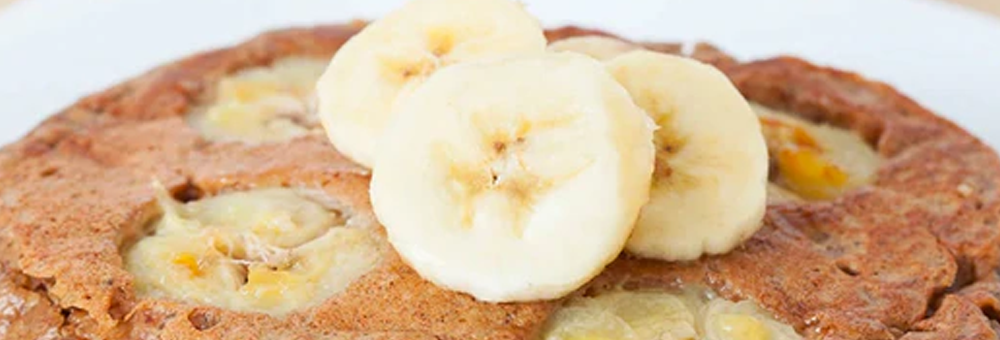 Banana protein pancake topped with sliced bananas on a white plate