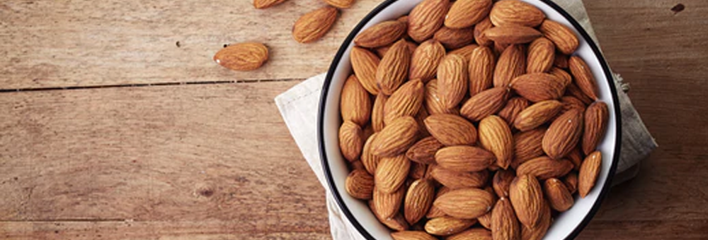 Close-up of a bowl of almonds on a white napkin on a wooden table illustrating a portable protein snack