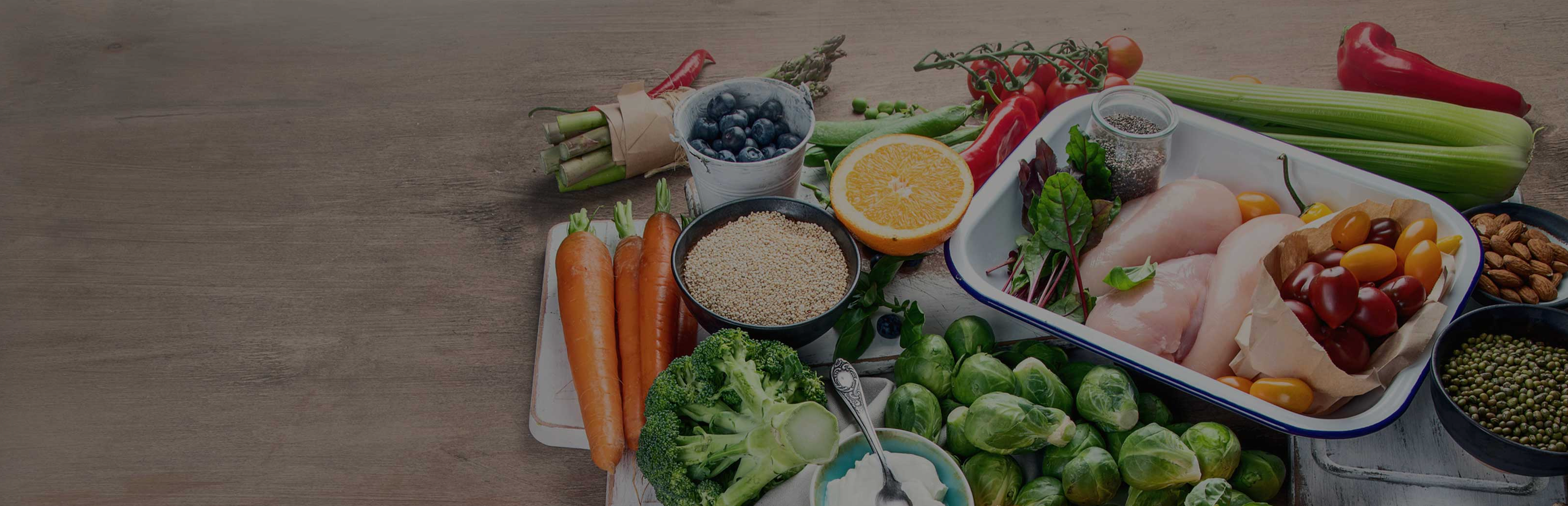 Tray of fresh vegetables and lean chicken for meal prep on a wooden table