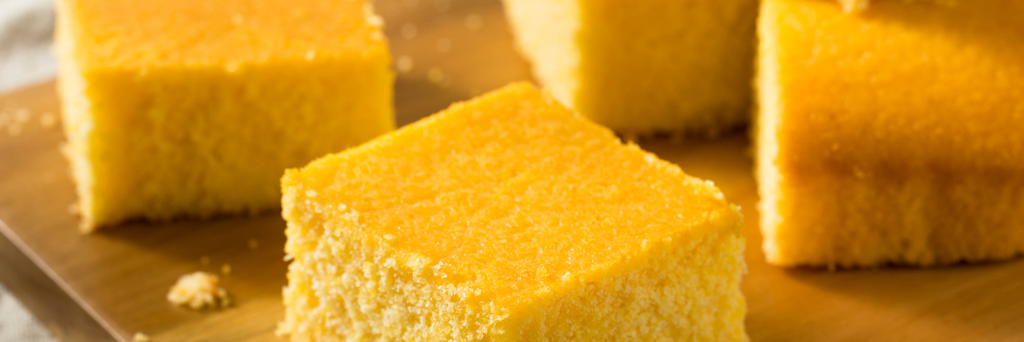 Close-up of Gaby’s Protein Corn Bread showcasing golden brown square pieces on a wooden surface