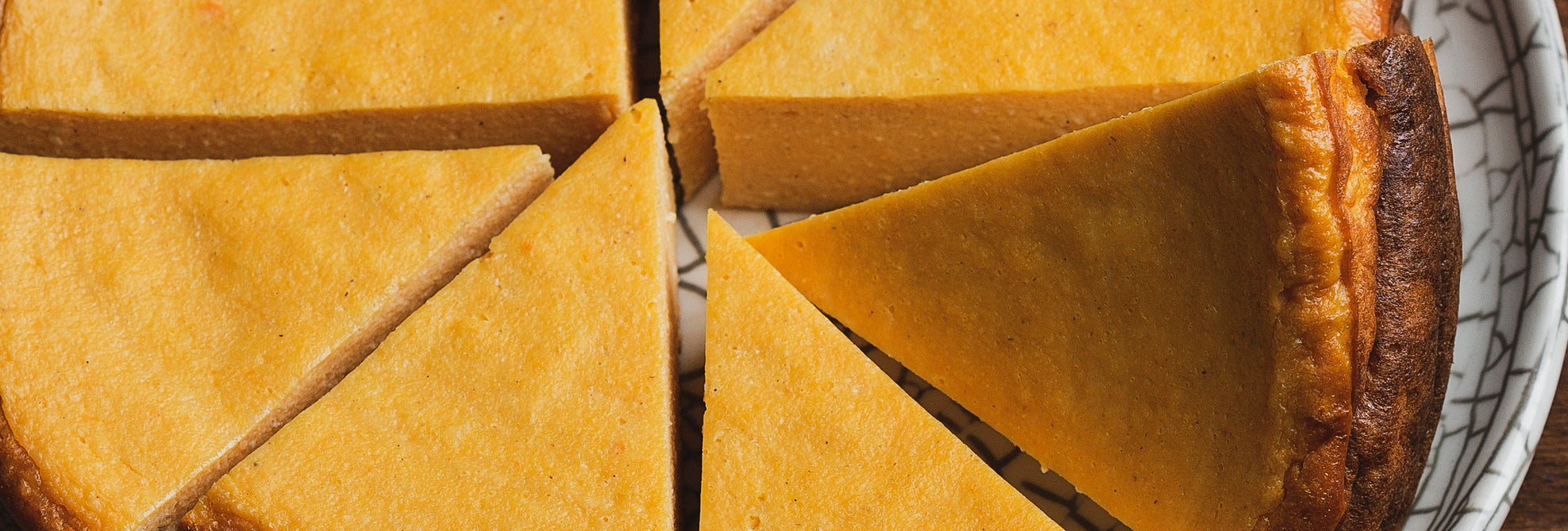 Top-down view of sliced crustless pumpkin protein pie showcasing smooth golden filling on a patterned white plate