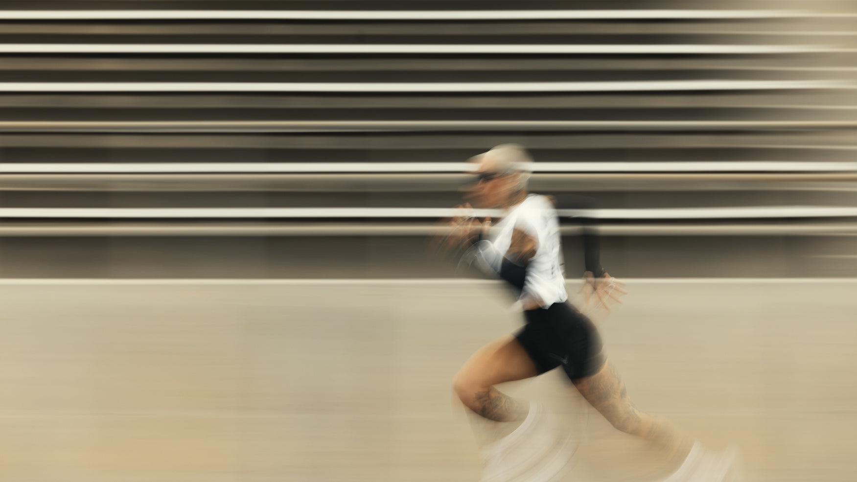 Runner sprinting past stadium bleachers with motion blur, outdoor summer training
