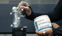 Kaged post-workout protein powder being scooped into a shaker, with electrolytes highlighted alongside. 