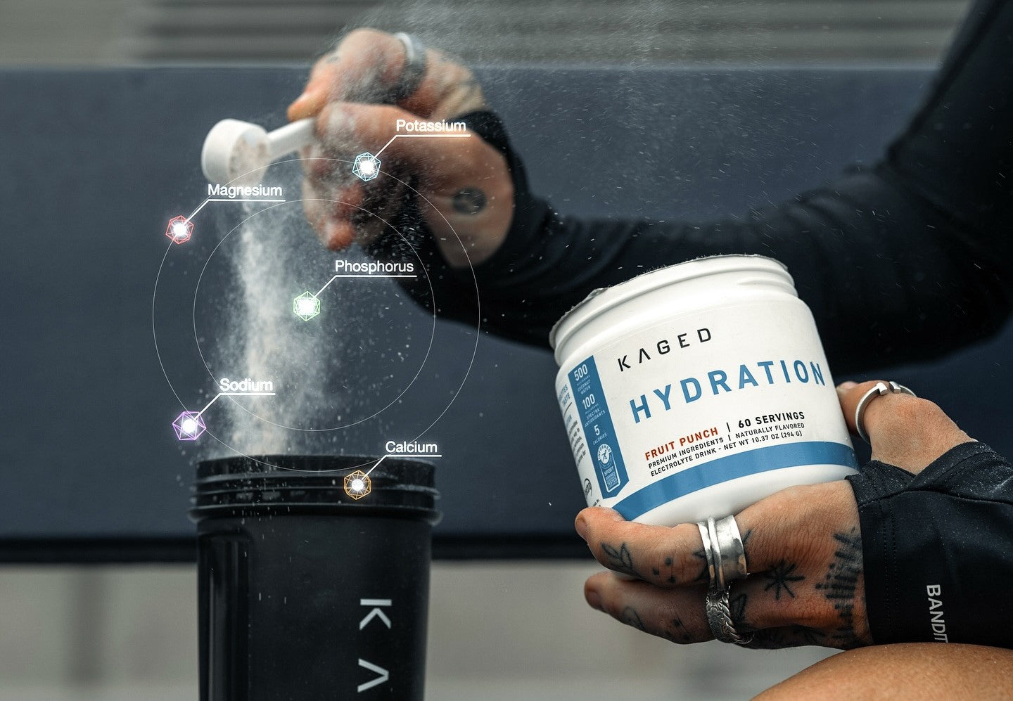 Powdered Kaged Hydration supplement being scooped into a black shaker bottle.