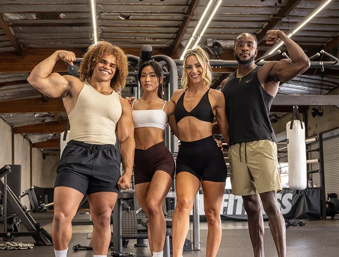 Four fit individuals posing and flexing together in a gym setting, fueled by Kaged supplements.