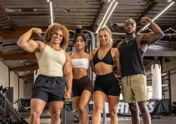 Four fit individuals posing and flexing together in a gym setting, fueled by Kaged supplements.